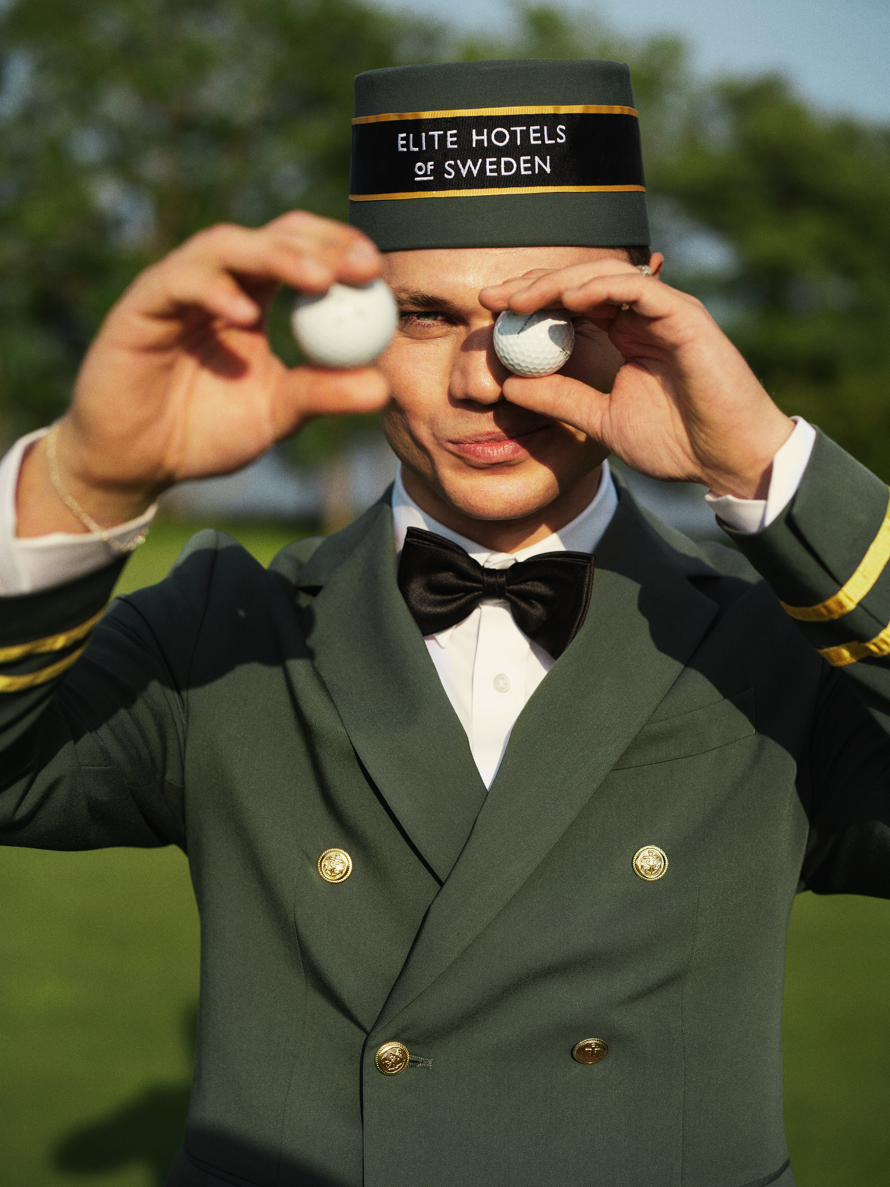 En glad tjej som sitter med en golfbag bredvid sig