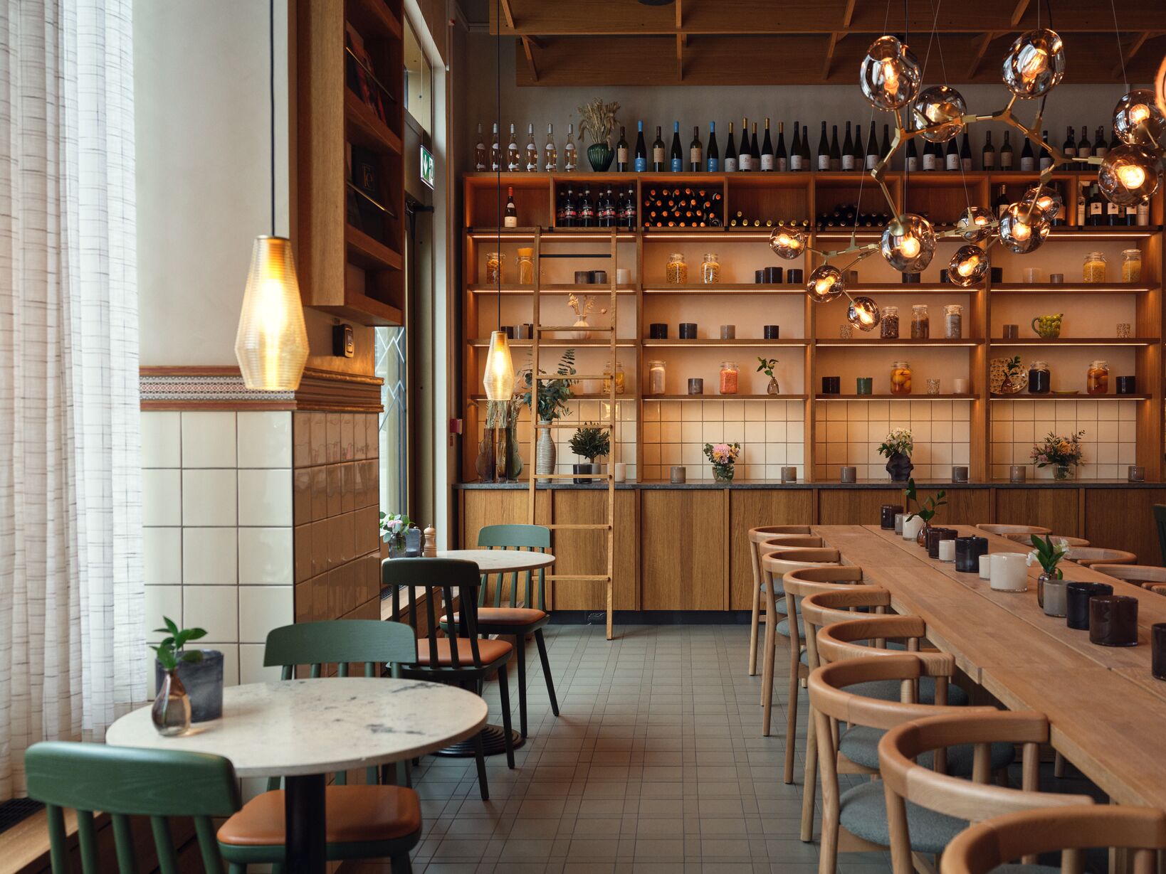 Modern restaurant interior with elegant lighting, wooden decor, and seating with throws