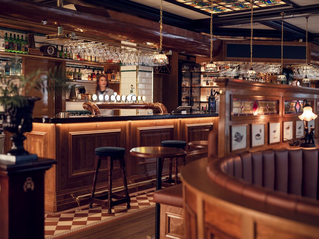 Elegant bar med träinredning och höga pallar