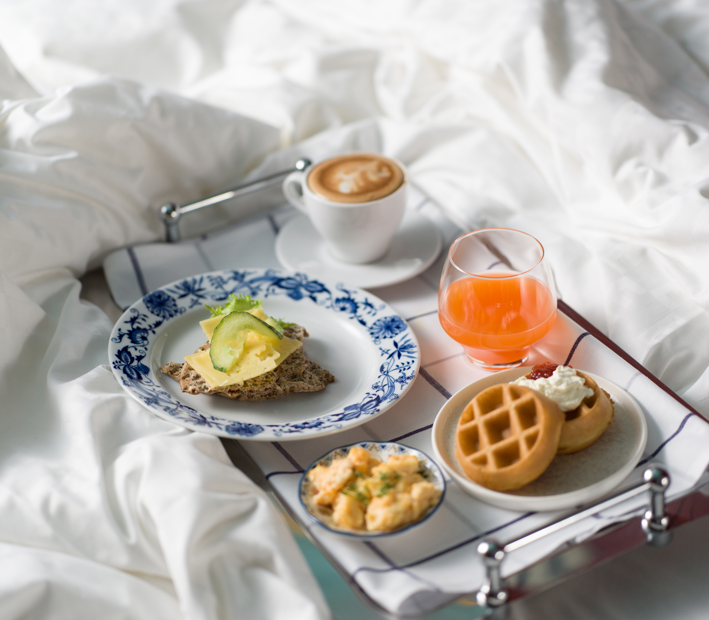 Breakfast tray with coffee and sandwich on hotel bed