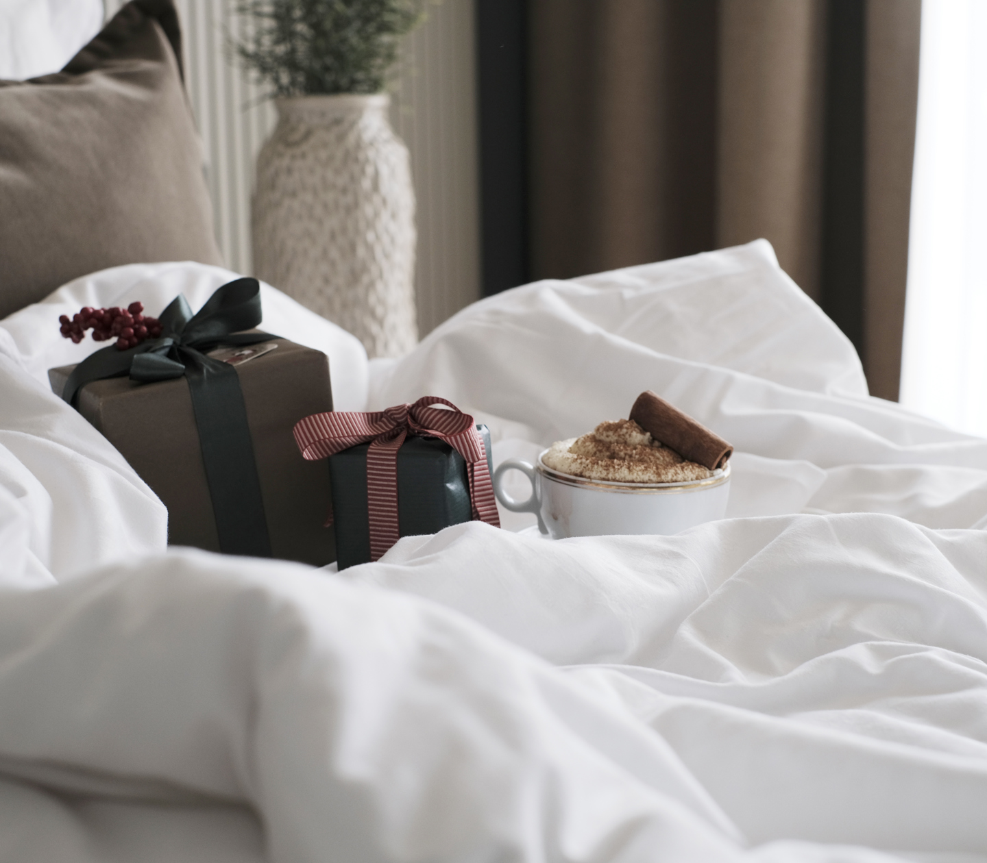 Christmas gifts and coffee cup on hotel bed