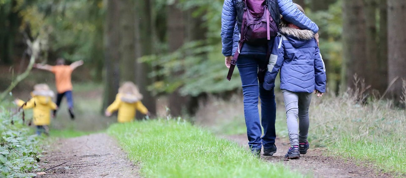 Barn och vuxen vandrar i skogen