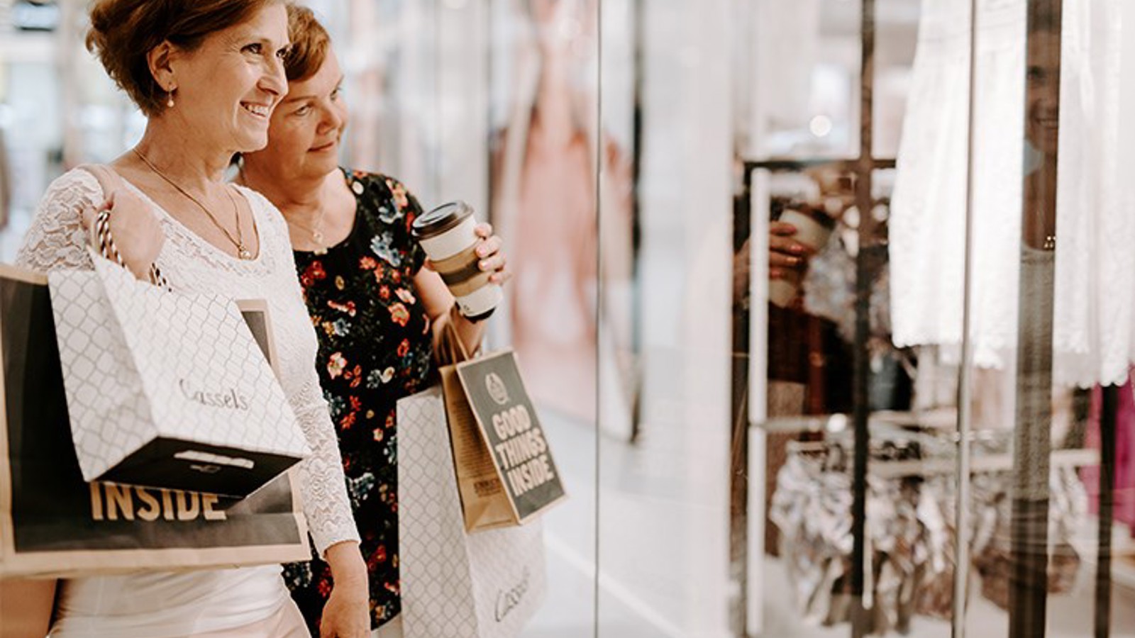 Två kvinnor med shoppingpåsar som ler