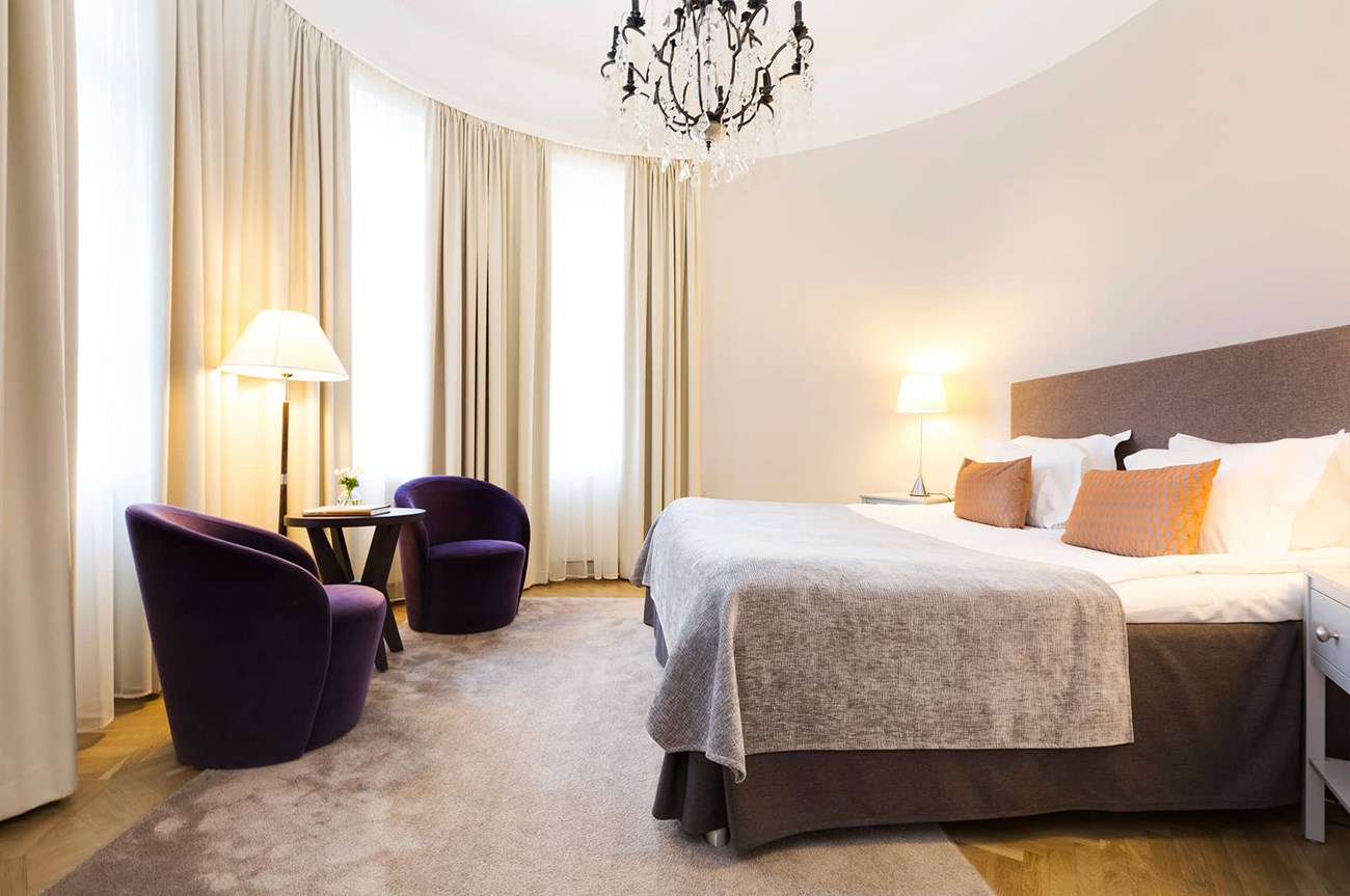 Large hotel room with bed and chairs