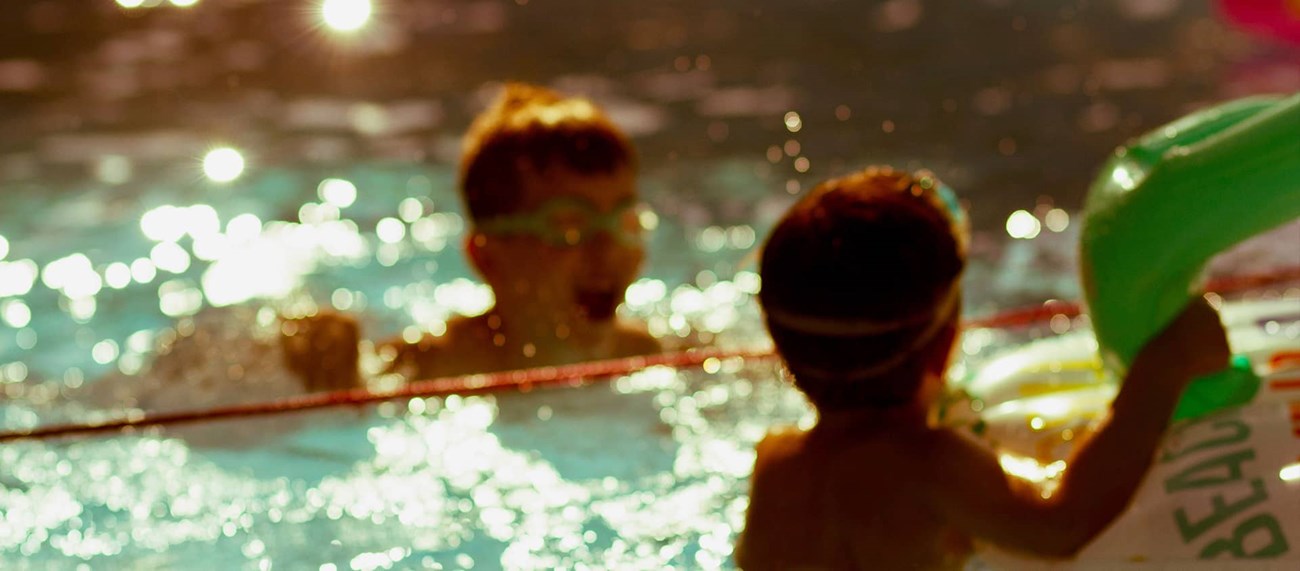 Barn som badar i bassäng. 