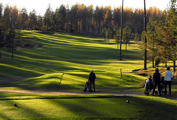 Golfbana med golfare i solnedgång