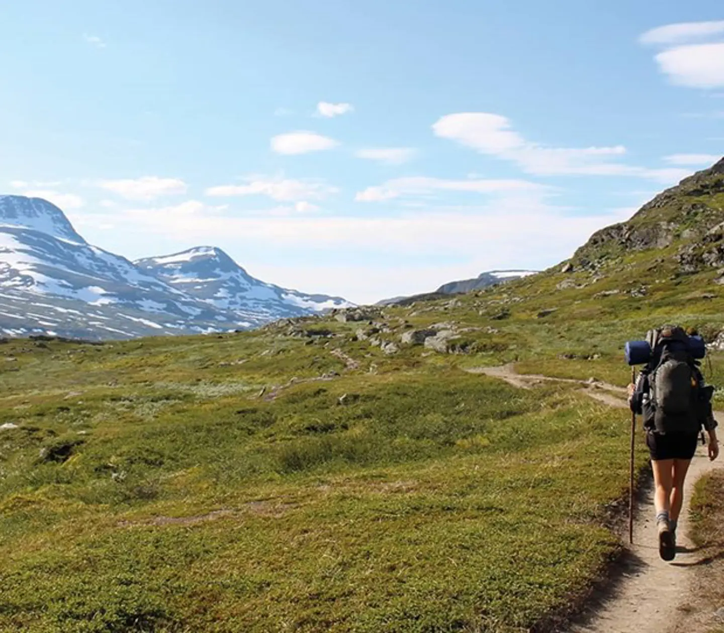 En vandrare som går längs en stig i ett berglandskap