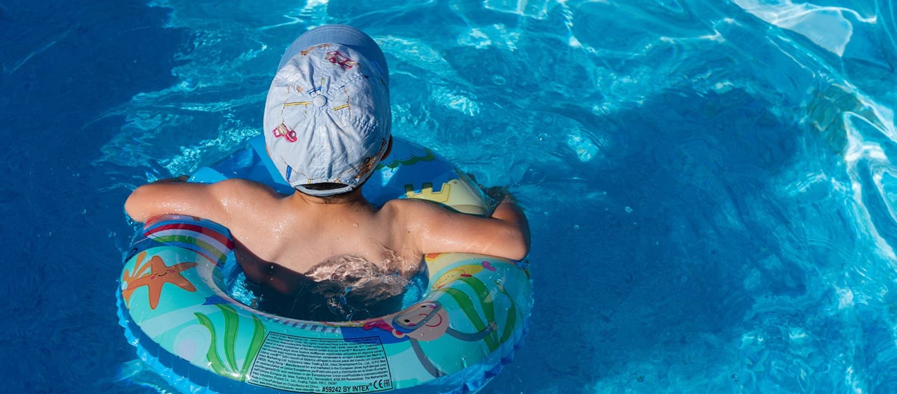 Ett barn simmar med en badring i en pool
