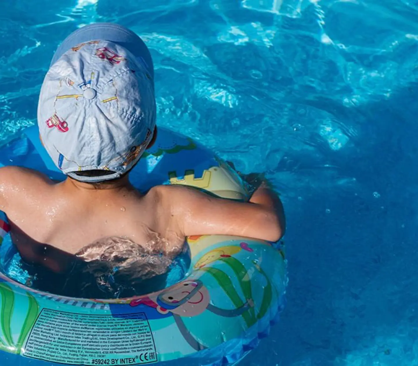 Ett barn simmar med en badring i en pool