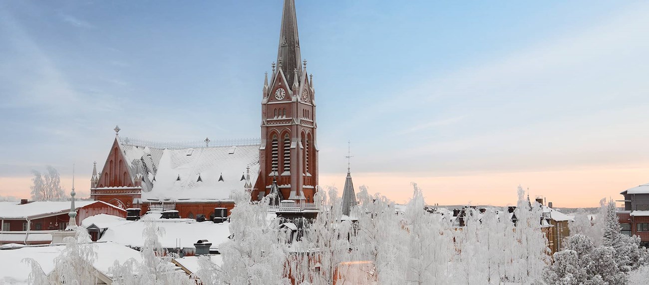 Snöigt stadslandskap med kyrka och blå himmel