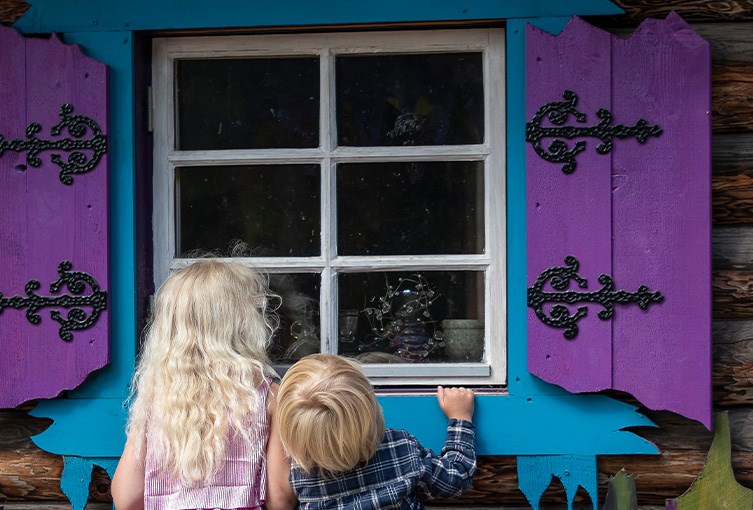 Två barn tittar in genom ett fönster i Tomteland
