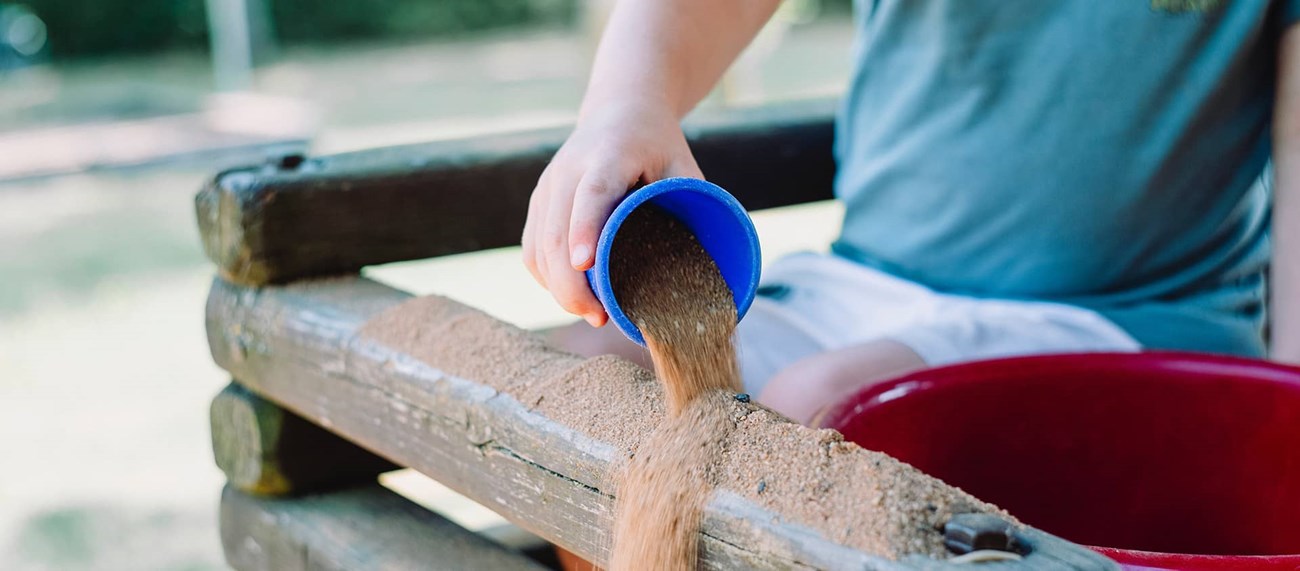 arm häller sand ur en kopp