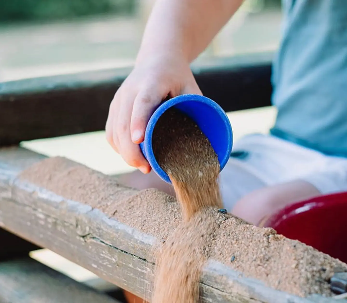 arm häller sand ur en kopp