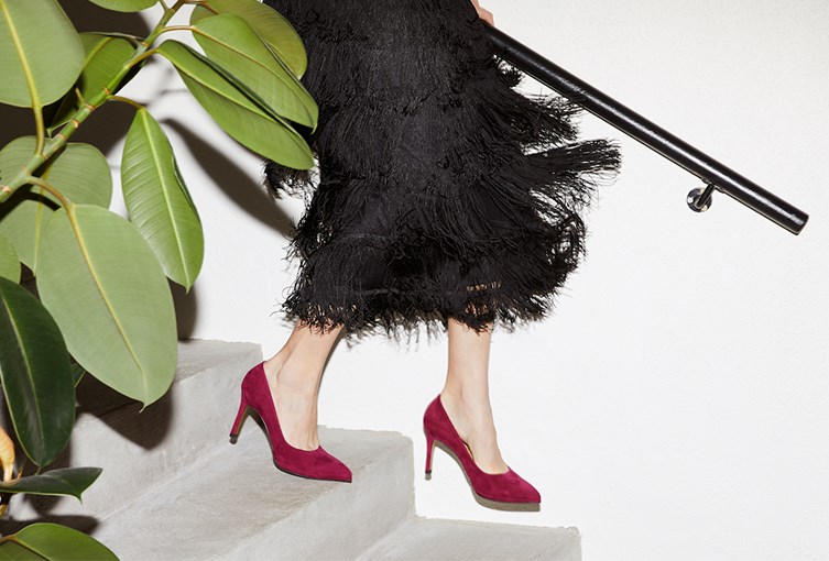 Kvinna i svart klänning och vinröda klackskor