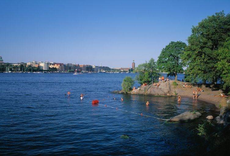 Badplats med klippor och bojar med lina för att skärma av