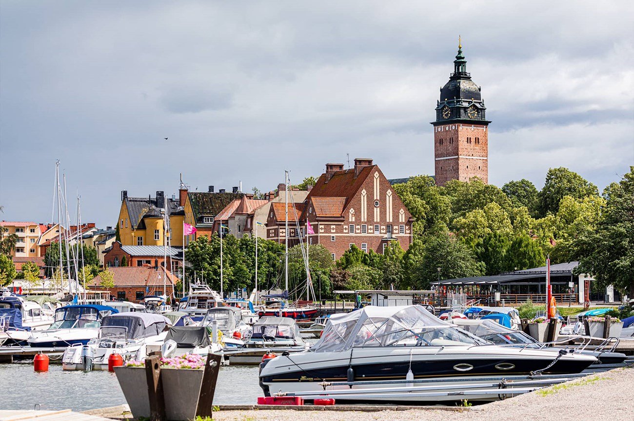 Hamn med båtar och Strängnäs Domkyrka som syns bland trädtopparna i bakgrunden