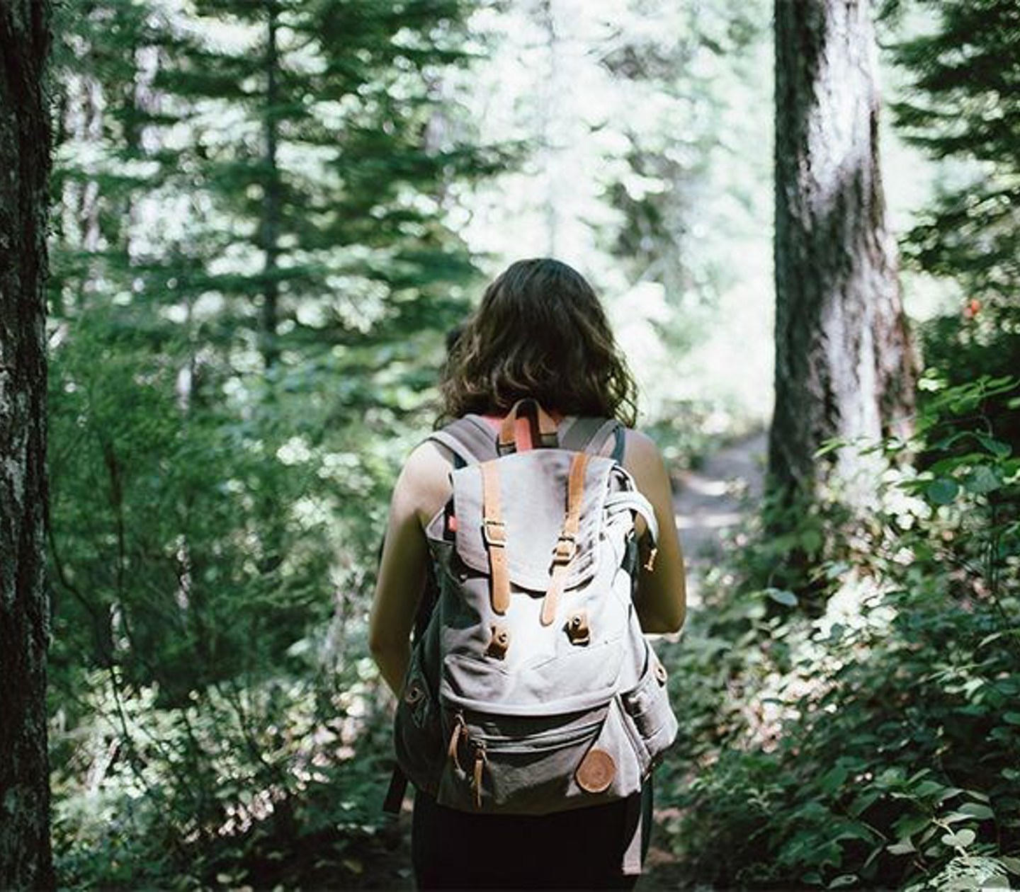 Kvinna med ryggsäck vandrar i skogen