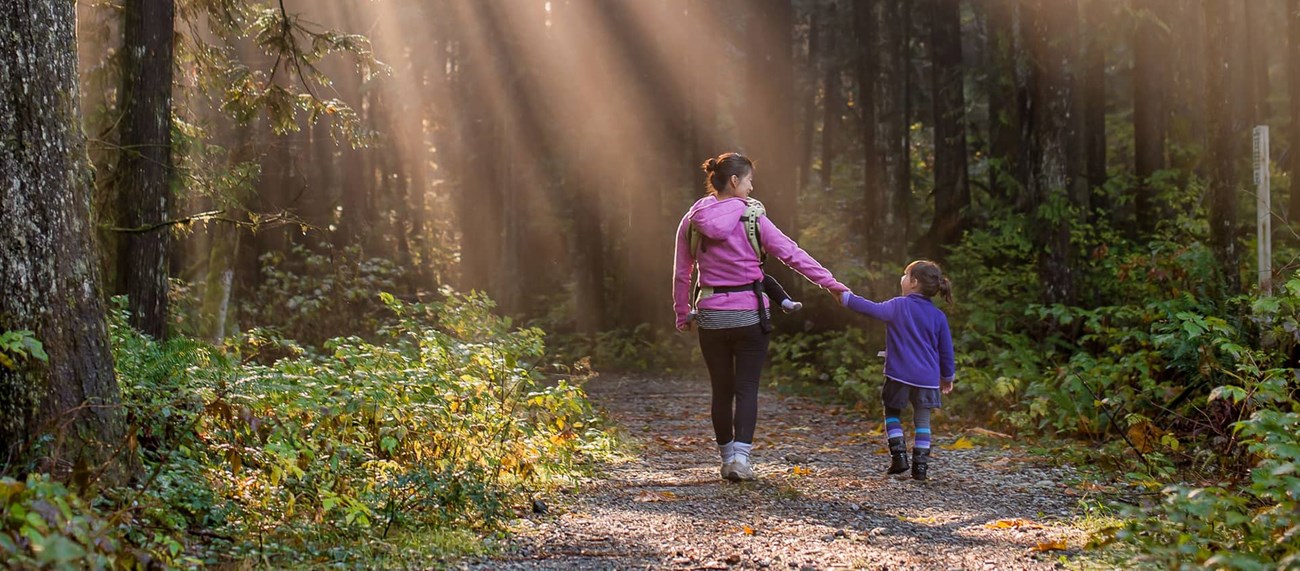 En vuxen och ett barn som håller varandra i hand, på promenad i skojen
