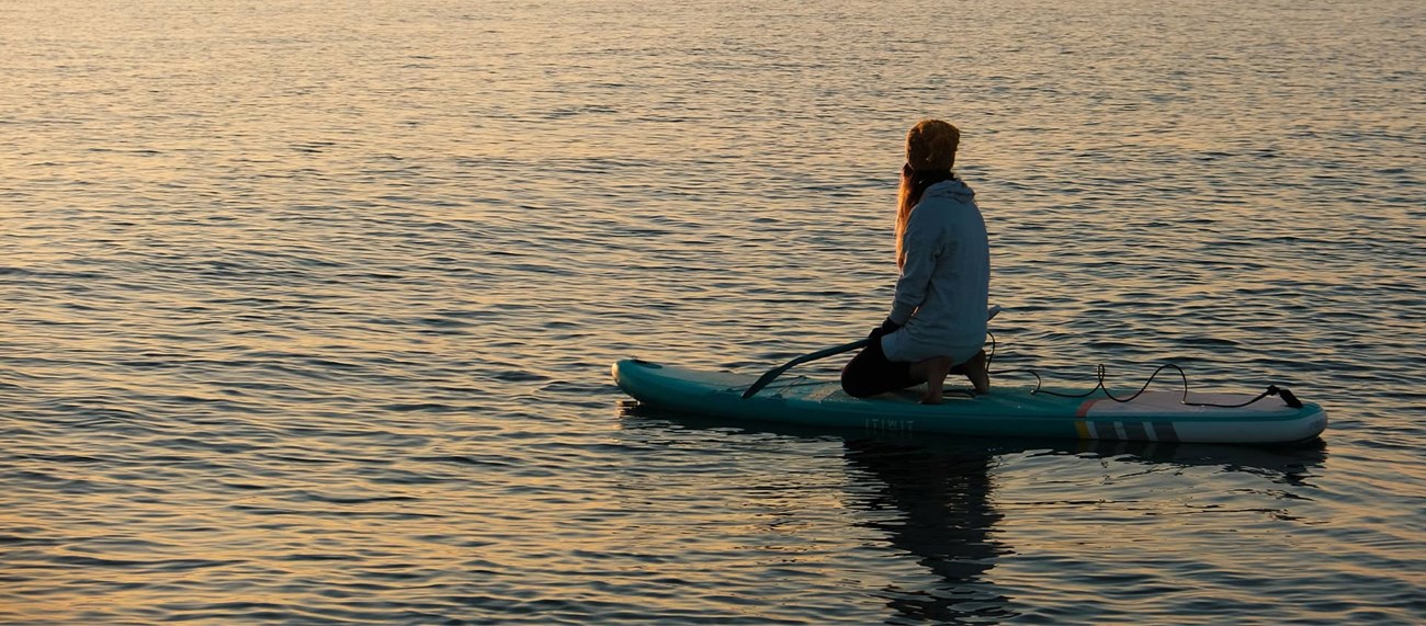 Tjej glider fram på knä på en SUP