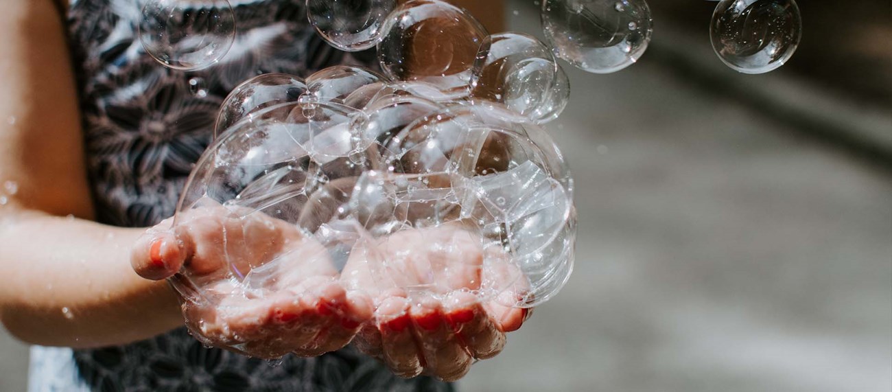 Händer som fångar såpbubblor 