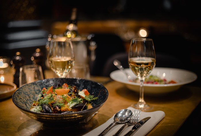 Elegant fine dining experience with gourmet salad and white wine glasses on a chic restaurant table.