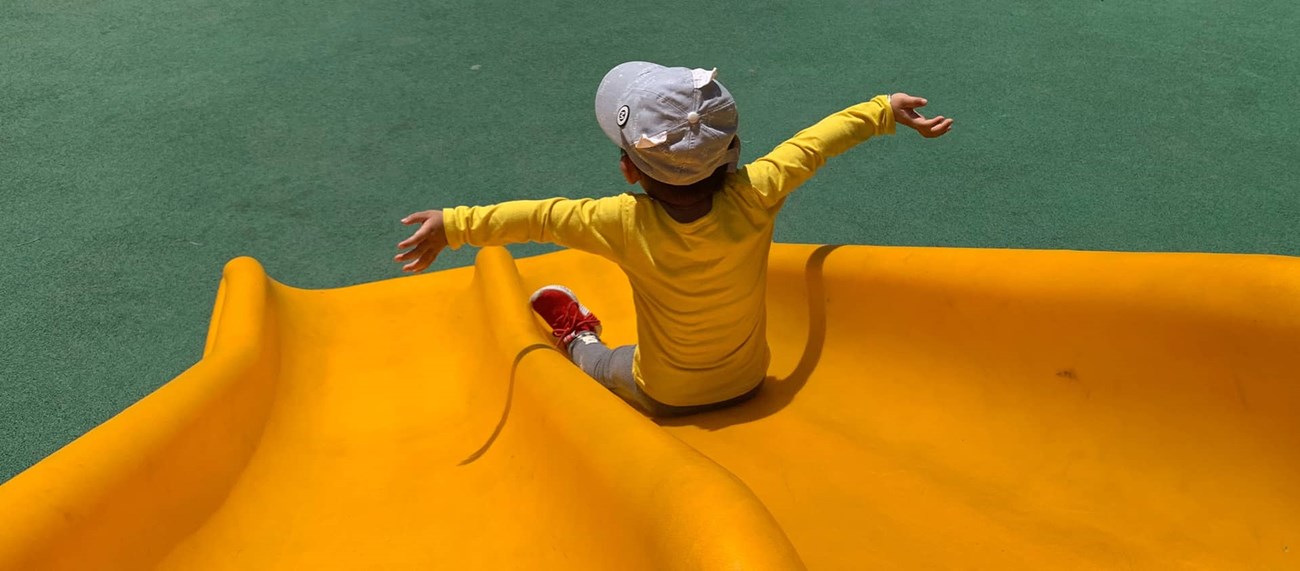 Barn i keps åker på gul ruschkana