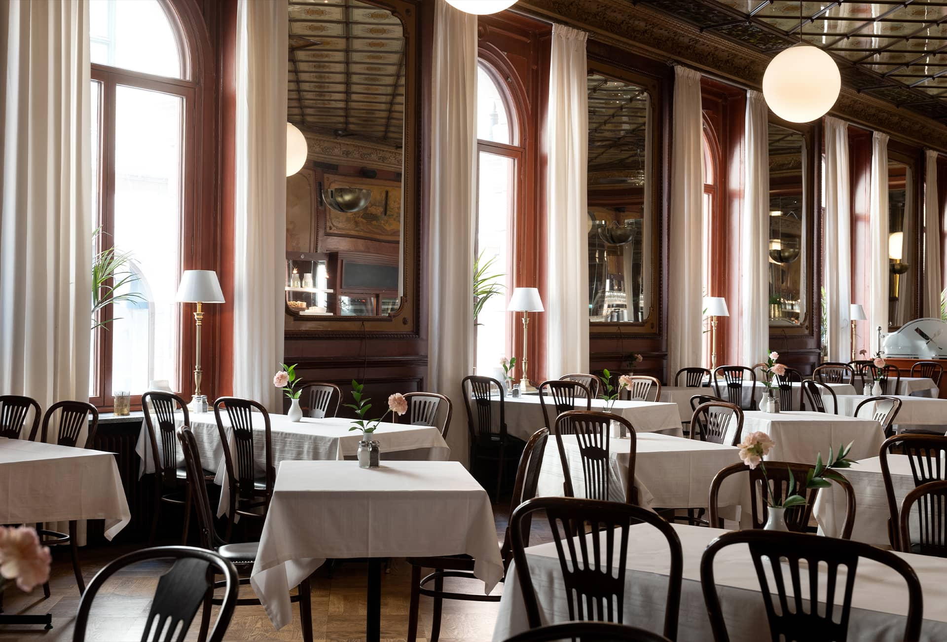 Fin matsal med speglar i taket och på väggarna, stora fönster, många bord med stolar