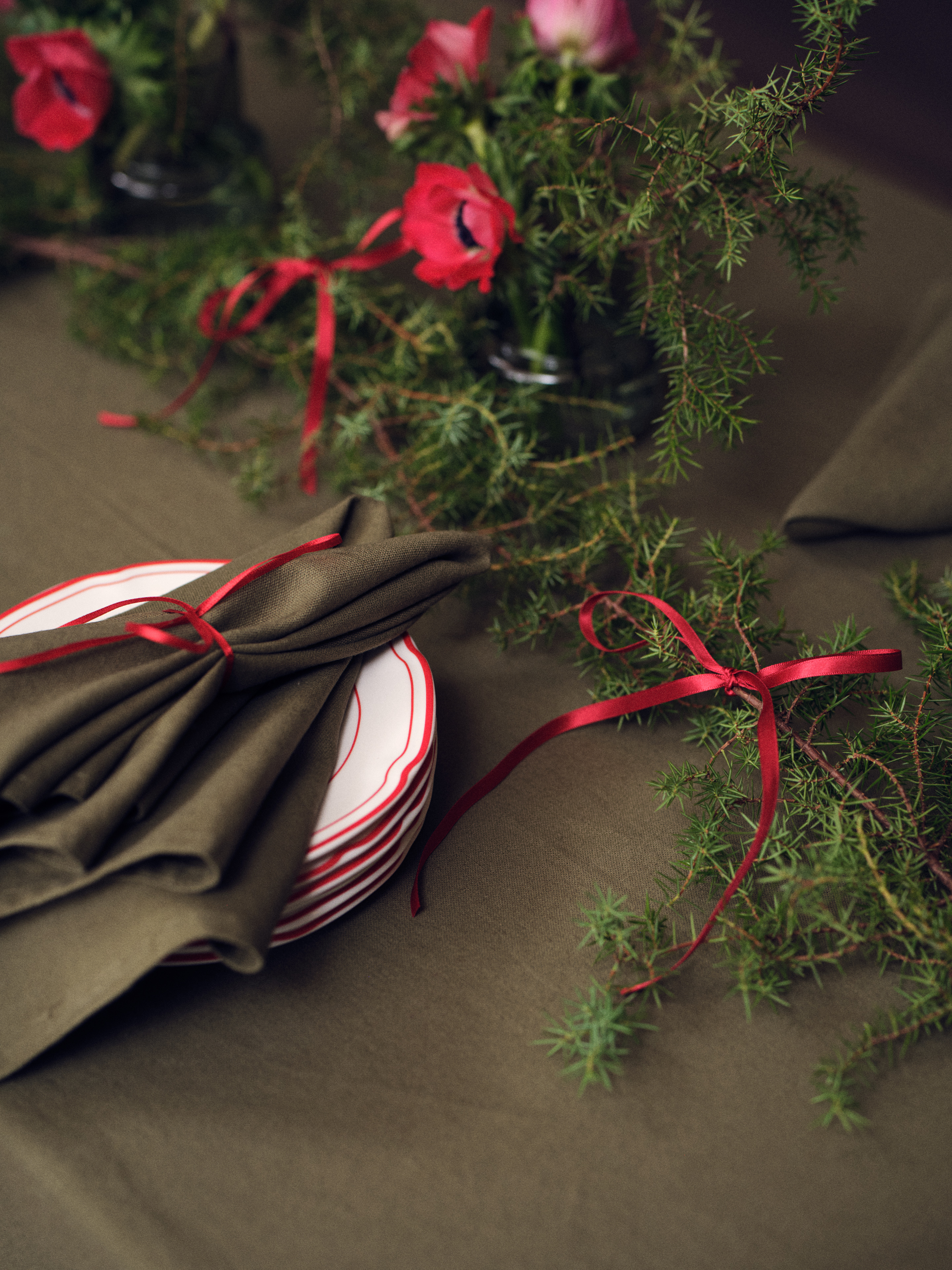 Holiday table setting with red ribbon and greenery