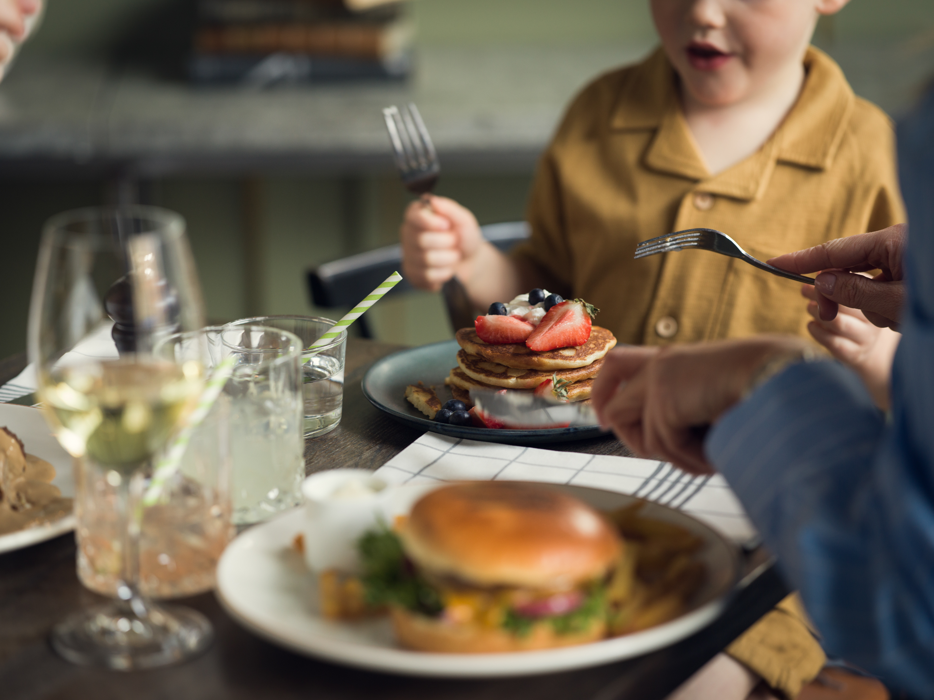 Barn som äter pannkakor och hamburgare på en restaurang