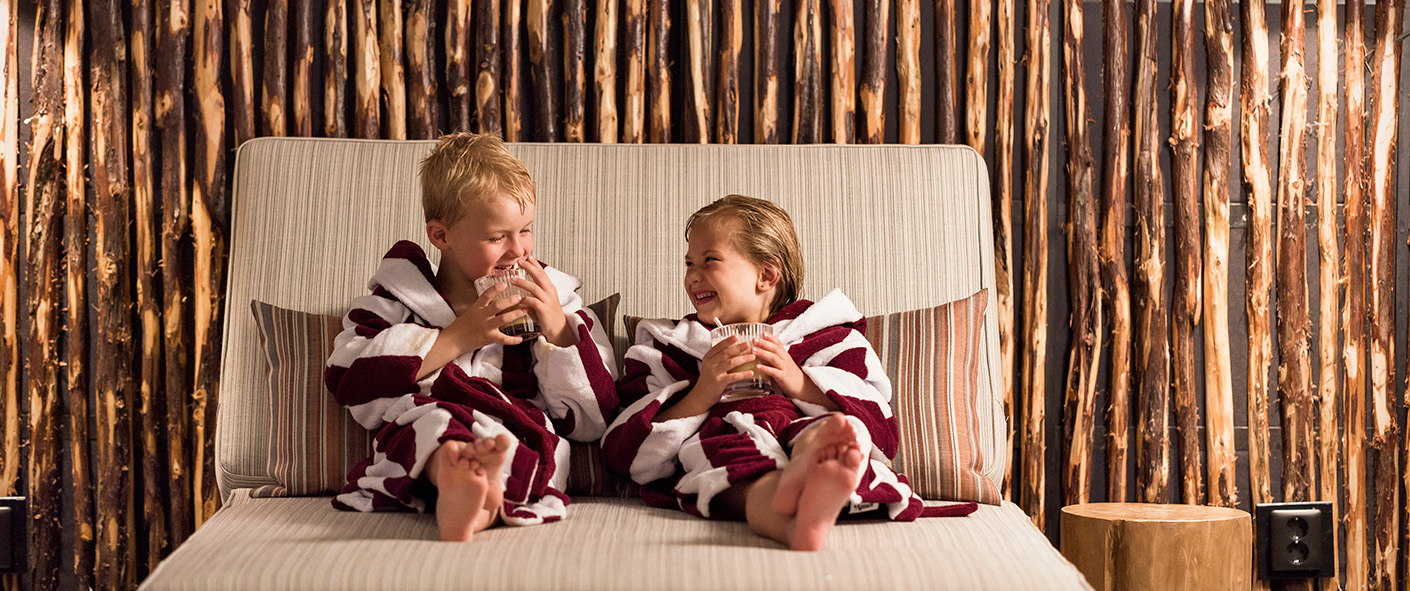 Barn i badrock sitter på en solstol