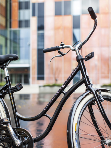 Svart cykel med Elite-tryck framför hotellfasad