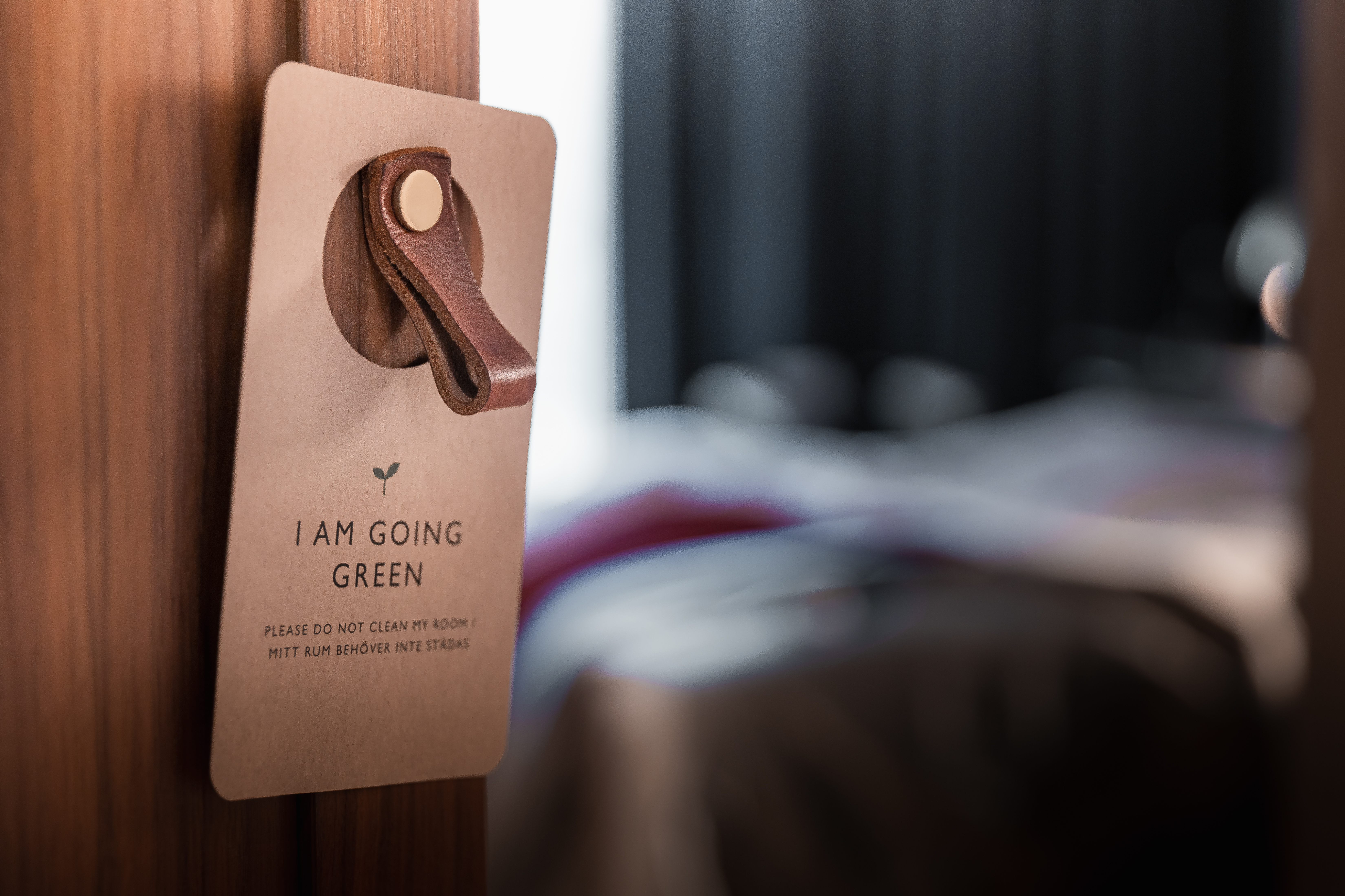 Miljöskylt upphängd på dörr med hotellrum i bakgrunden