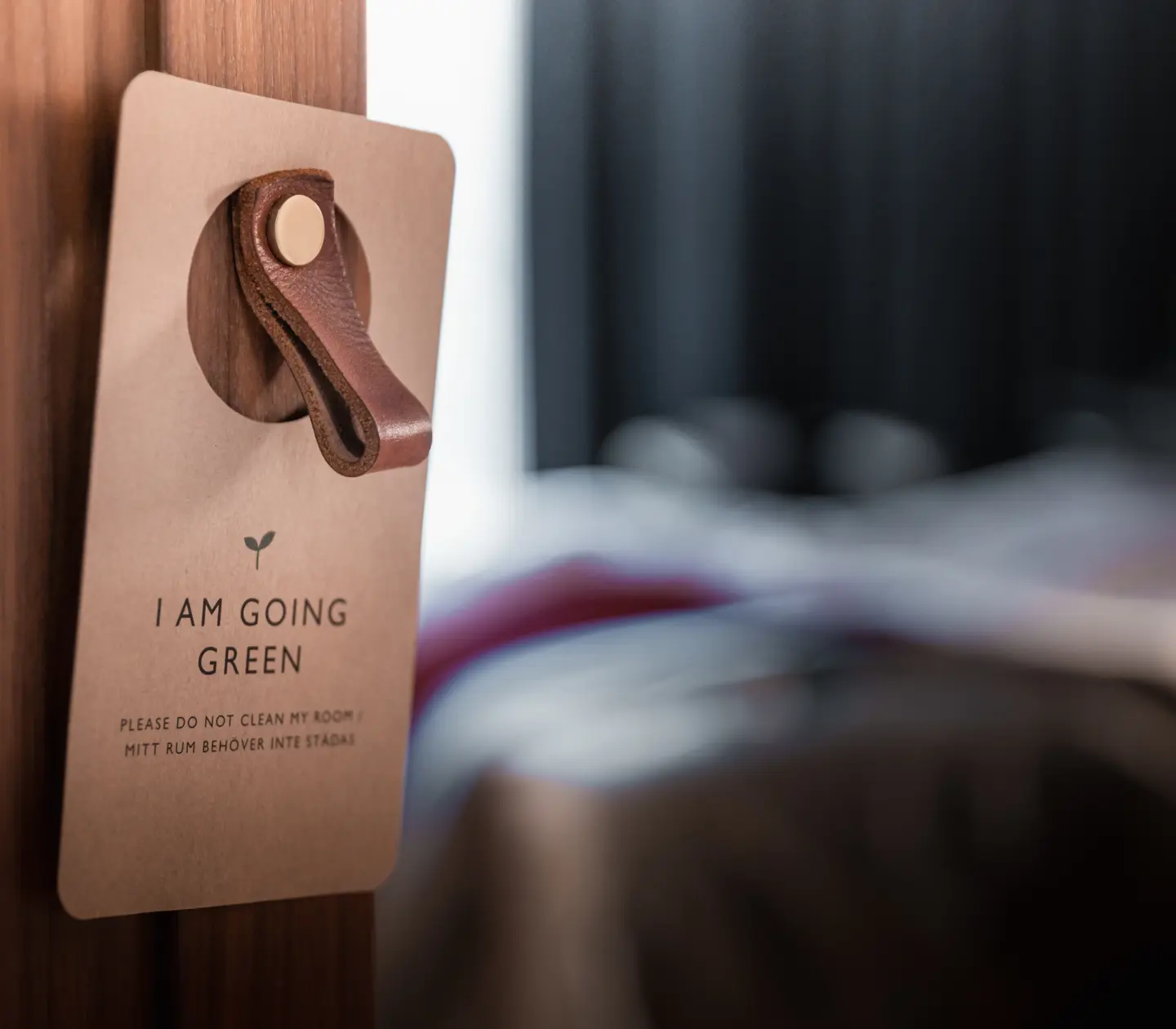 Environmental sign hung on door with hotel room in background