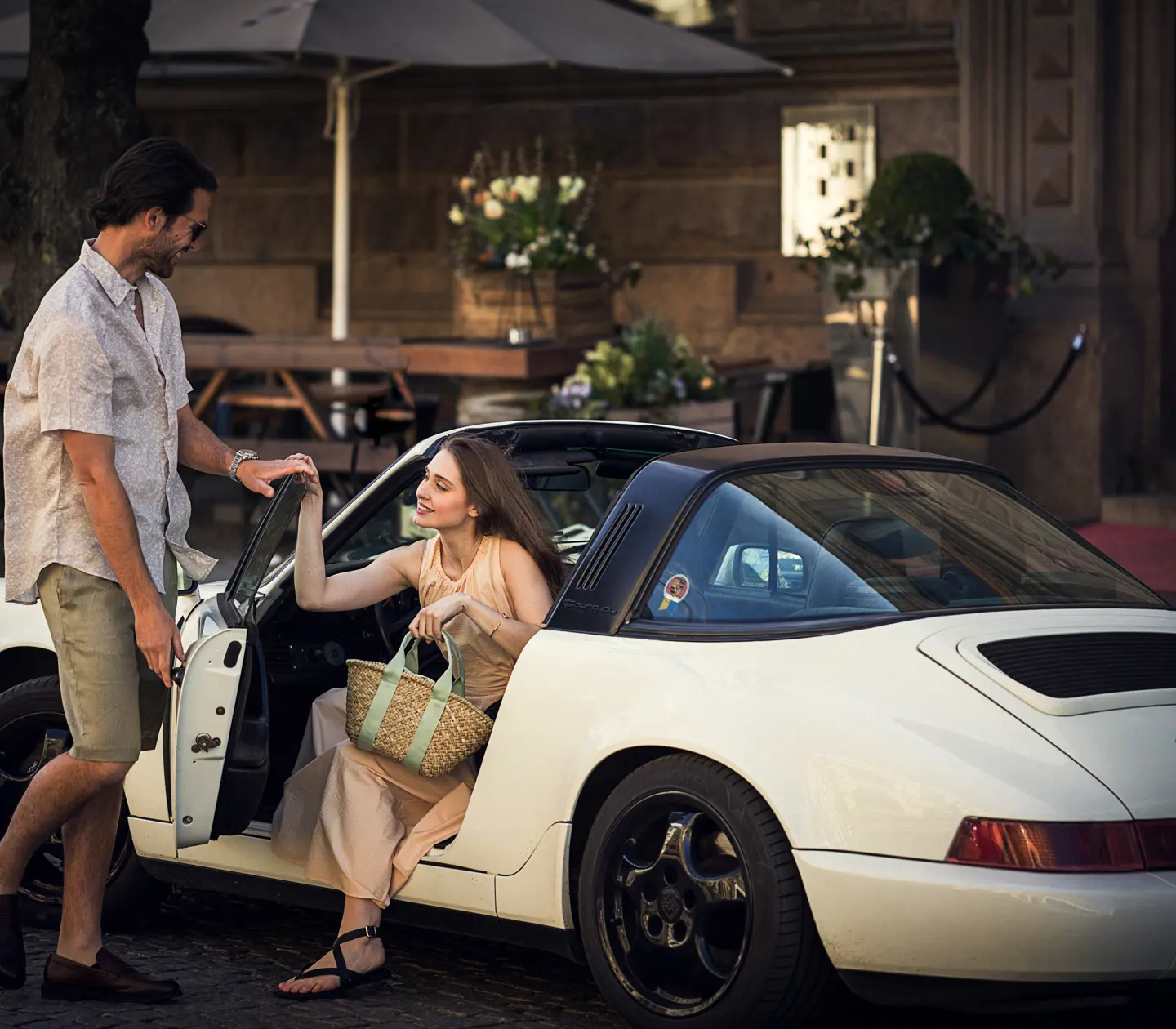 Woman jumping out of white sports car and a man opening the door