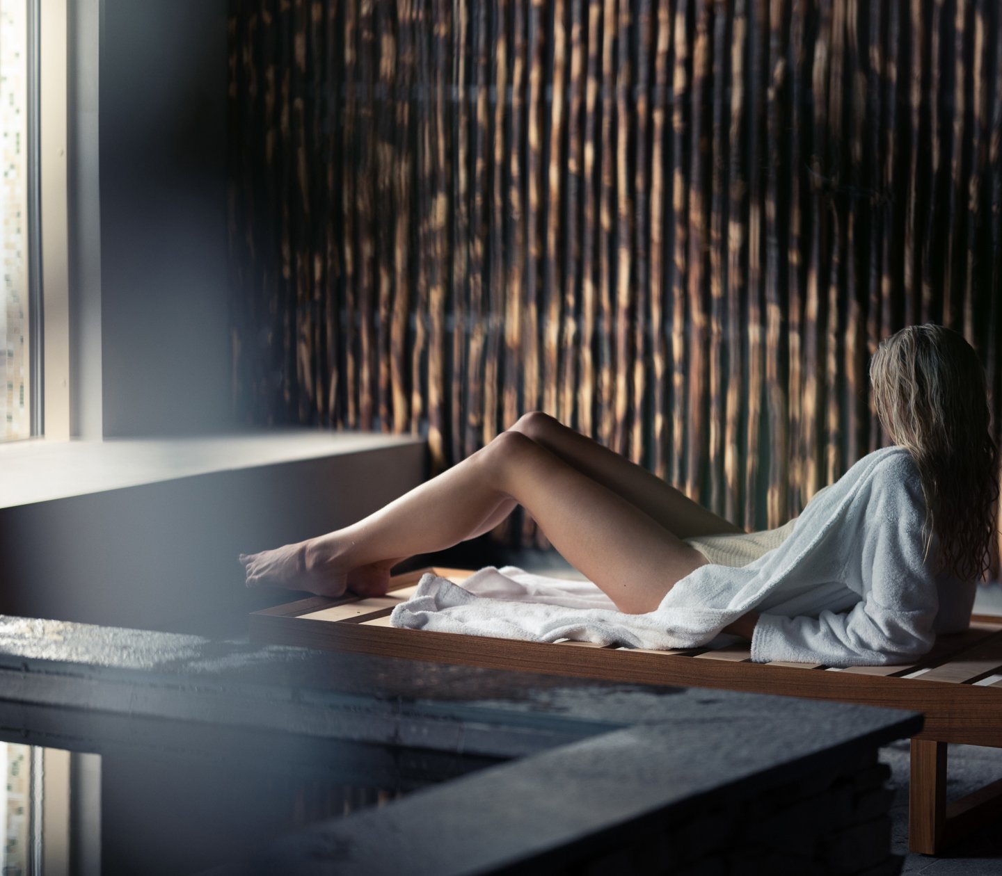 Spa environment with a woman in a bathrobe lying on a sunbed