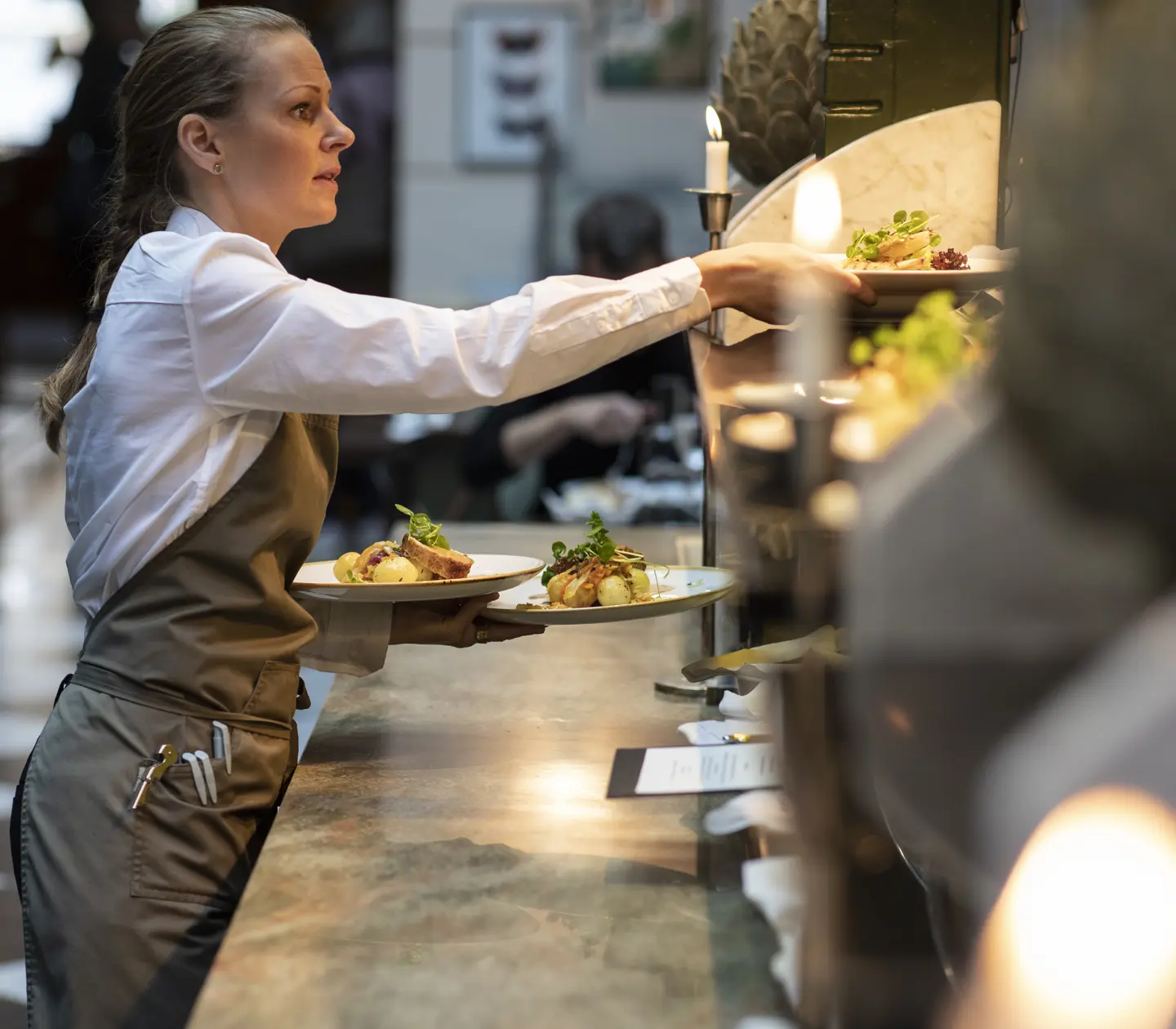 Woman in apron with plates in hand