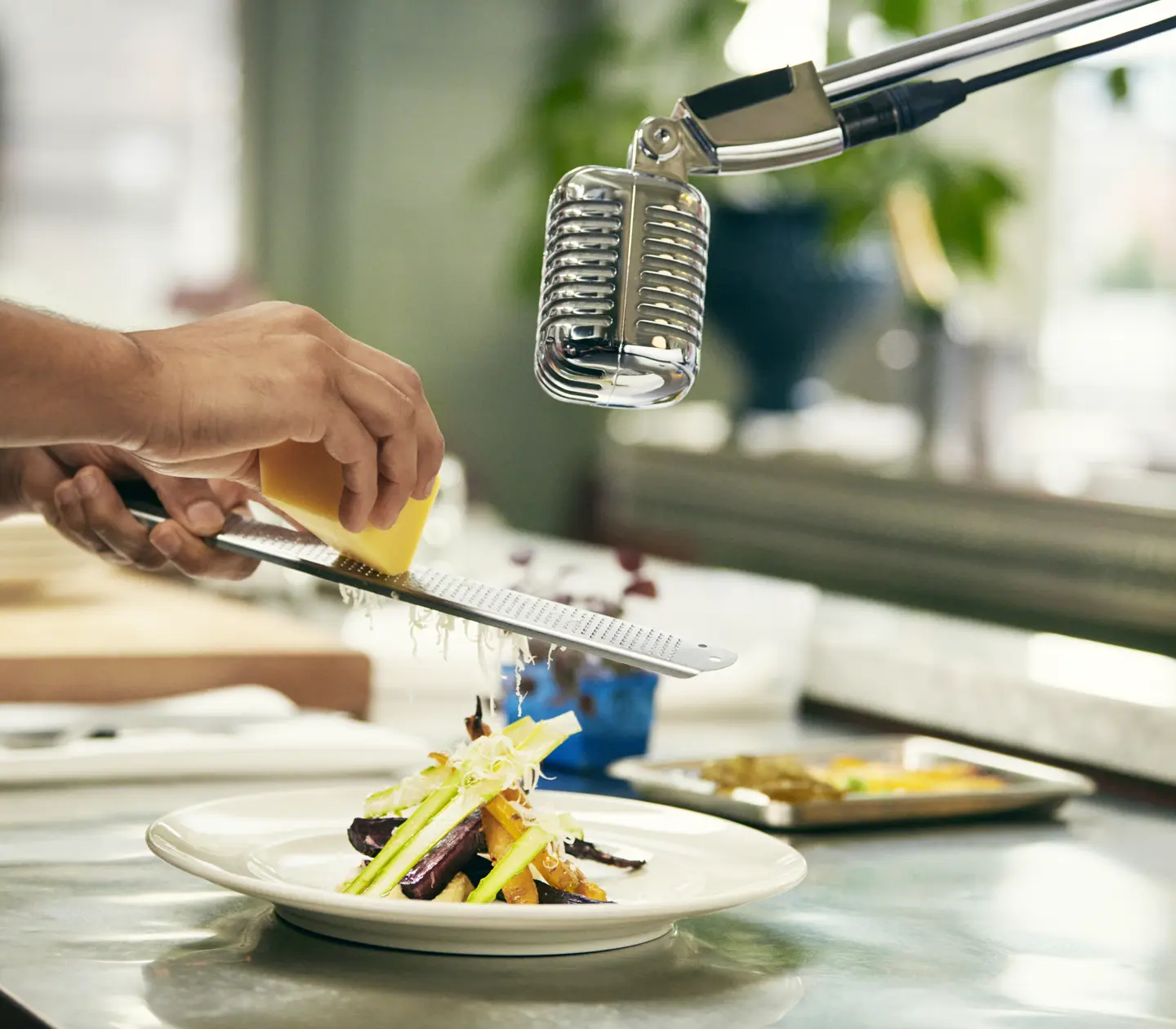 Man grating cheese over dish and microphone above