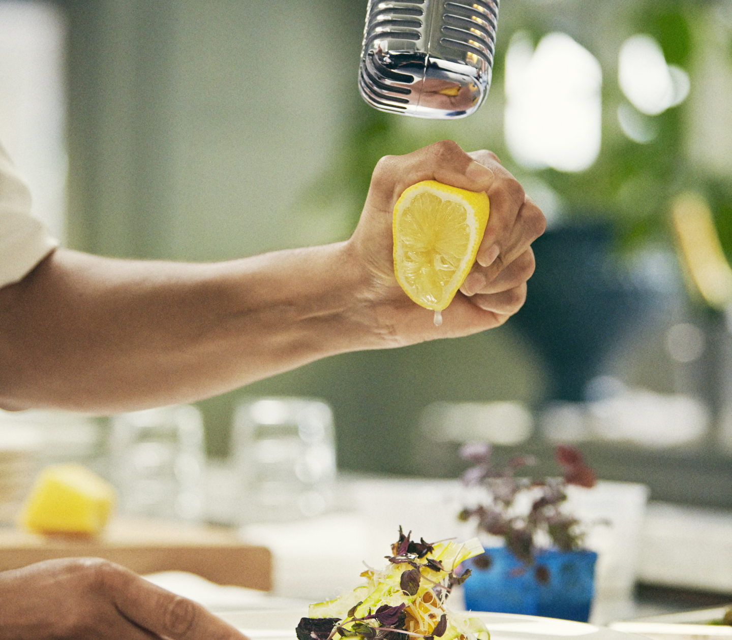 Man squeezing the juice out of a lemon over plate of food