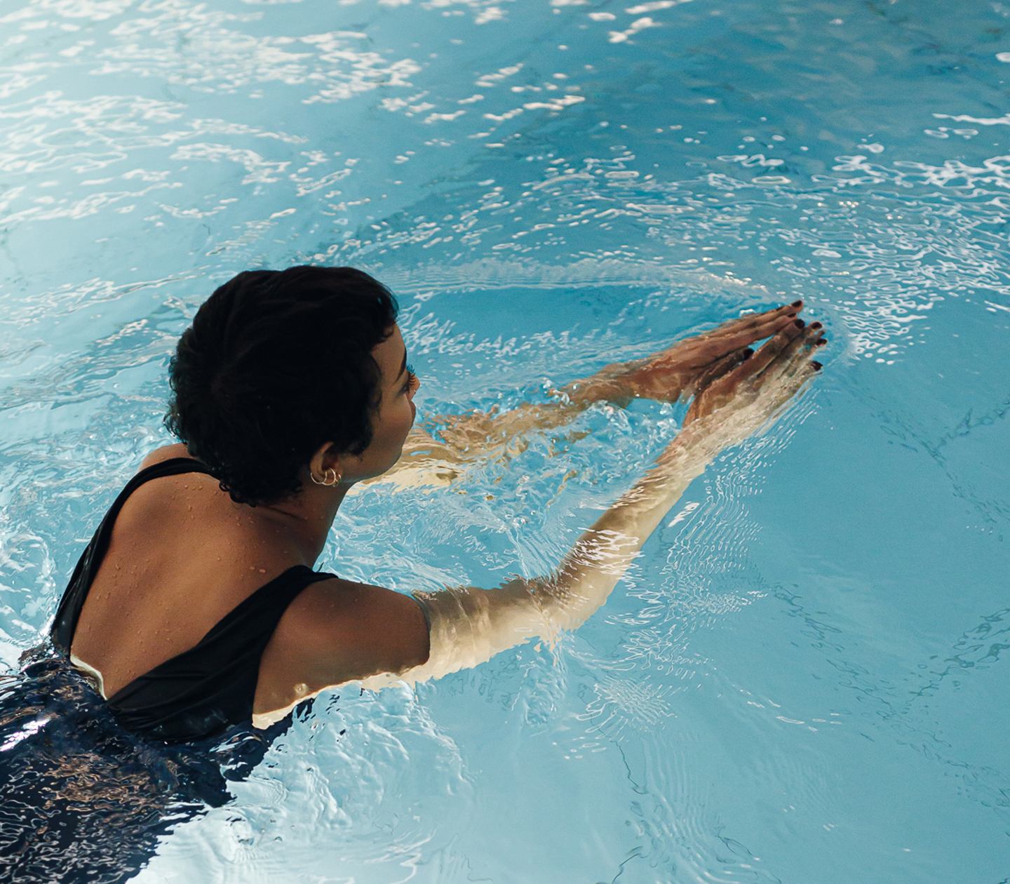 Woman in black swimsuit swimming in pool