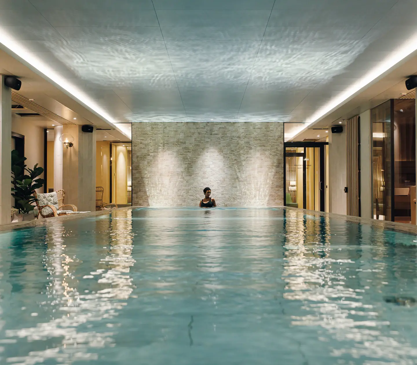 Spamiljö med pool, solsängar och kvinna i vattnet