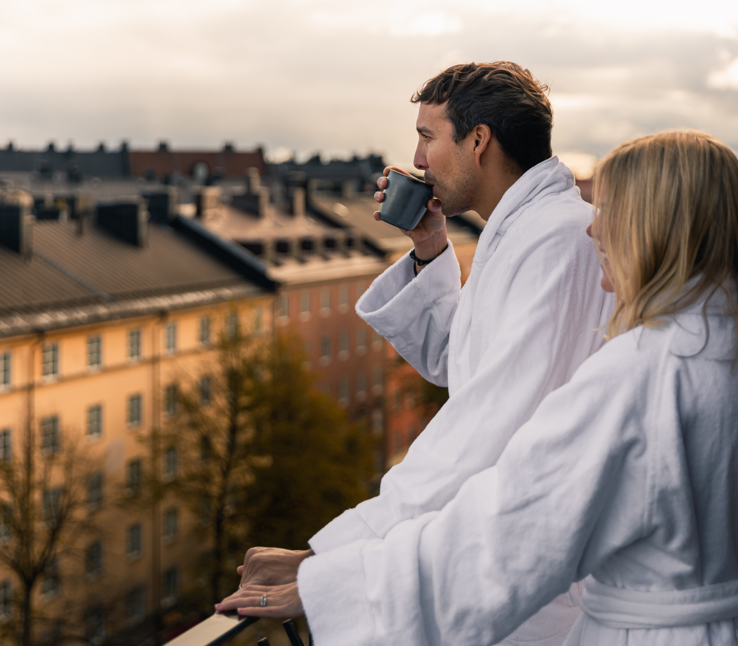 Couple standing in dressing gowns looking out over rooftops