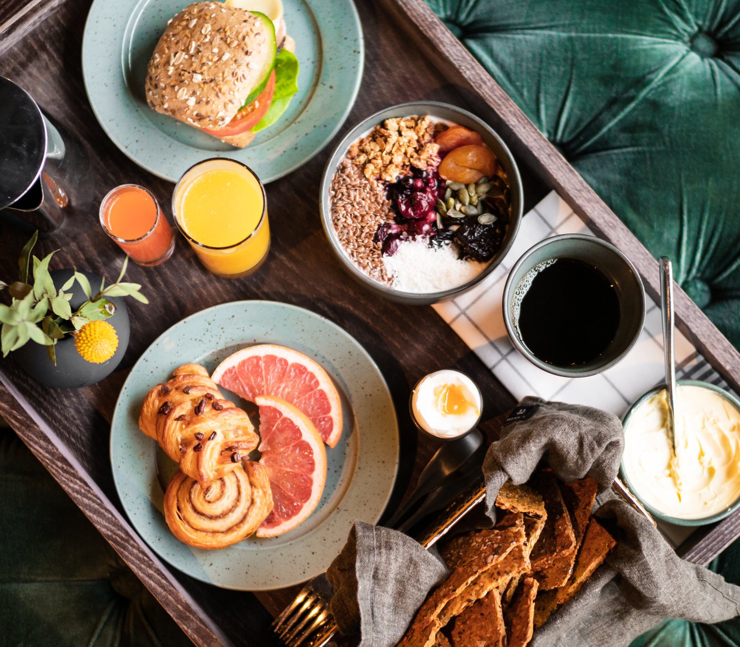 Breakfast tray on green cloth with sandwiches, coffee and fruit