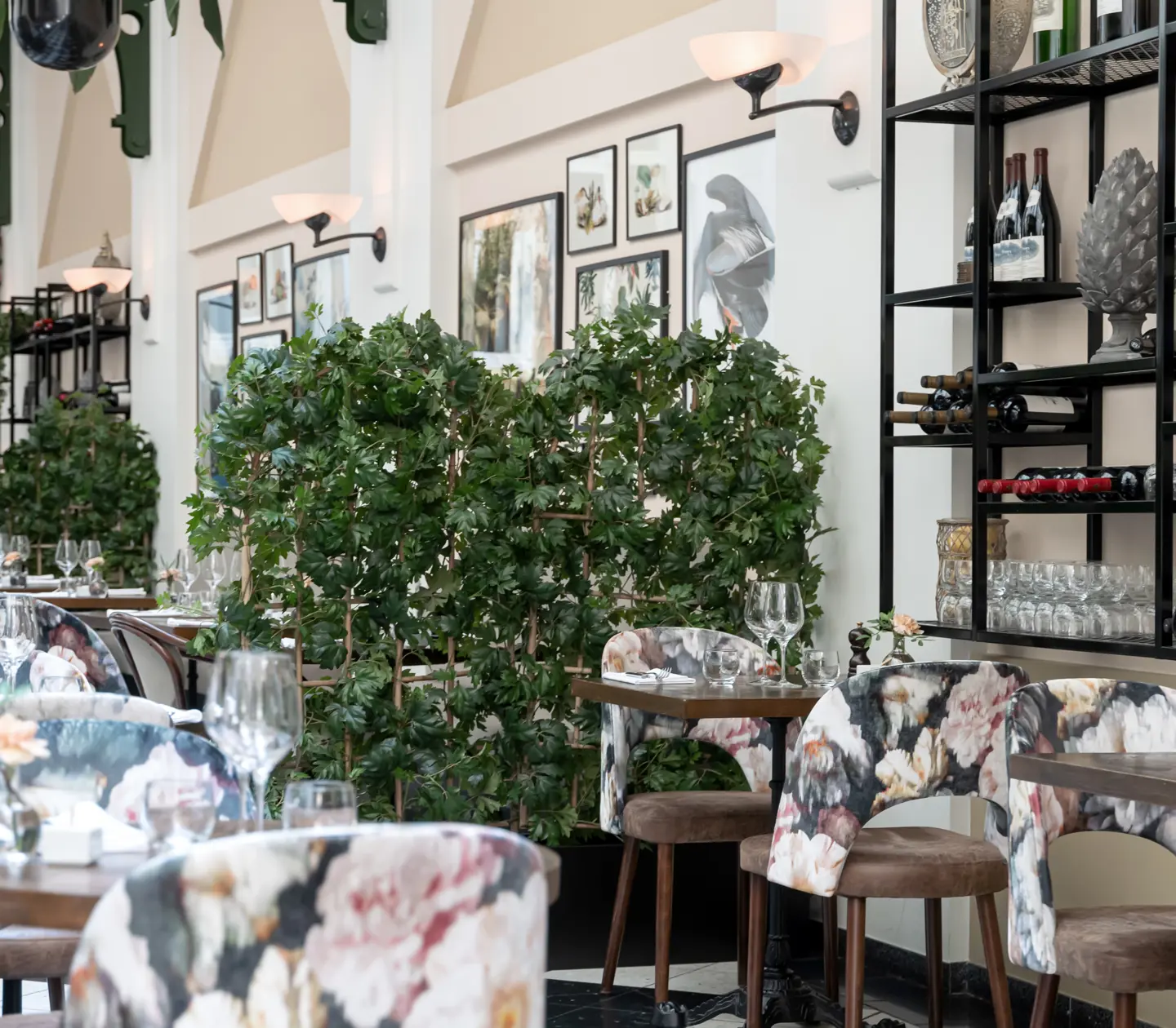 Elegant restaurangmiljö med dukade bord, växter, viner och tavlor