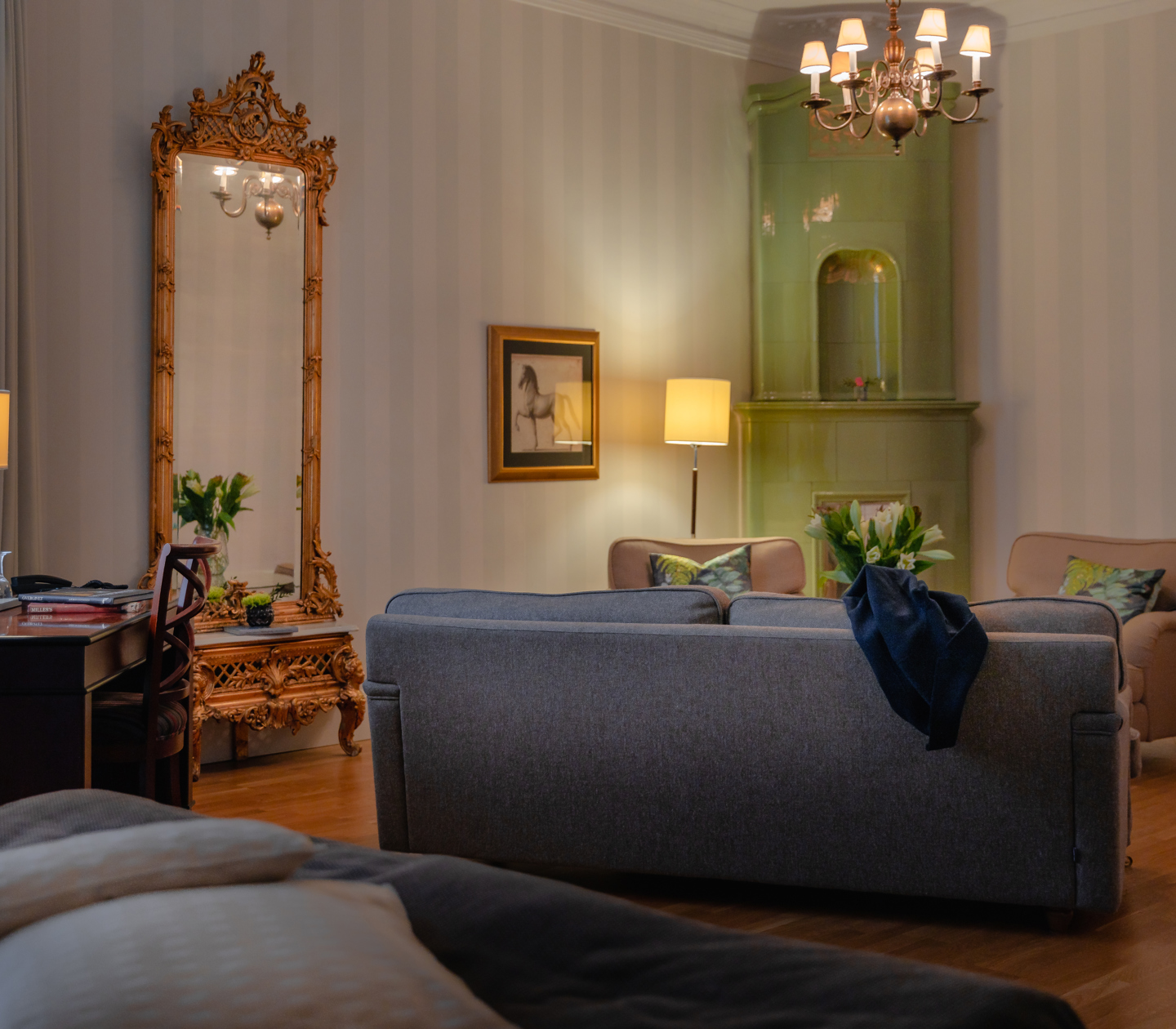 Suite with sofa, golden mirror and green tiled stove