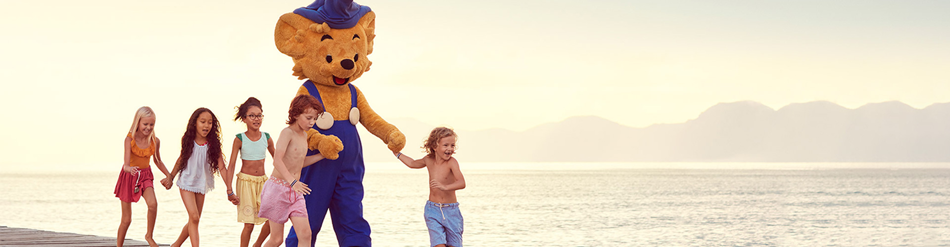 Barn springer på en strand med Bamse