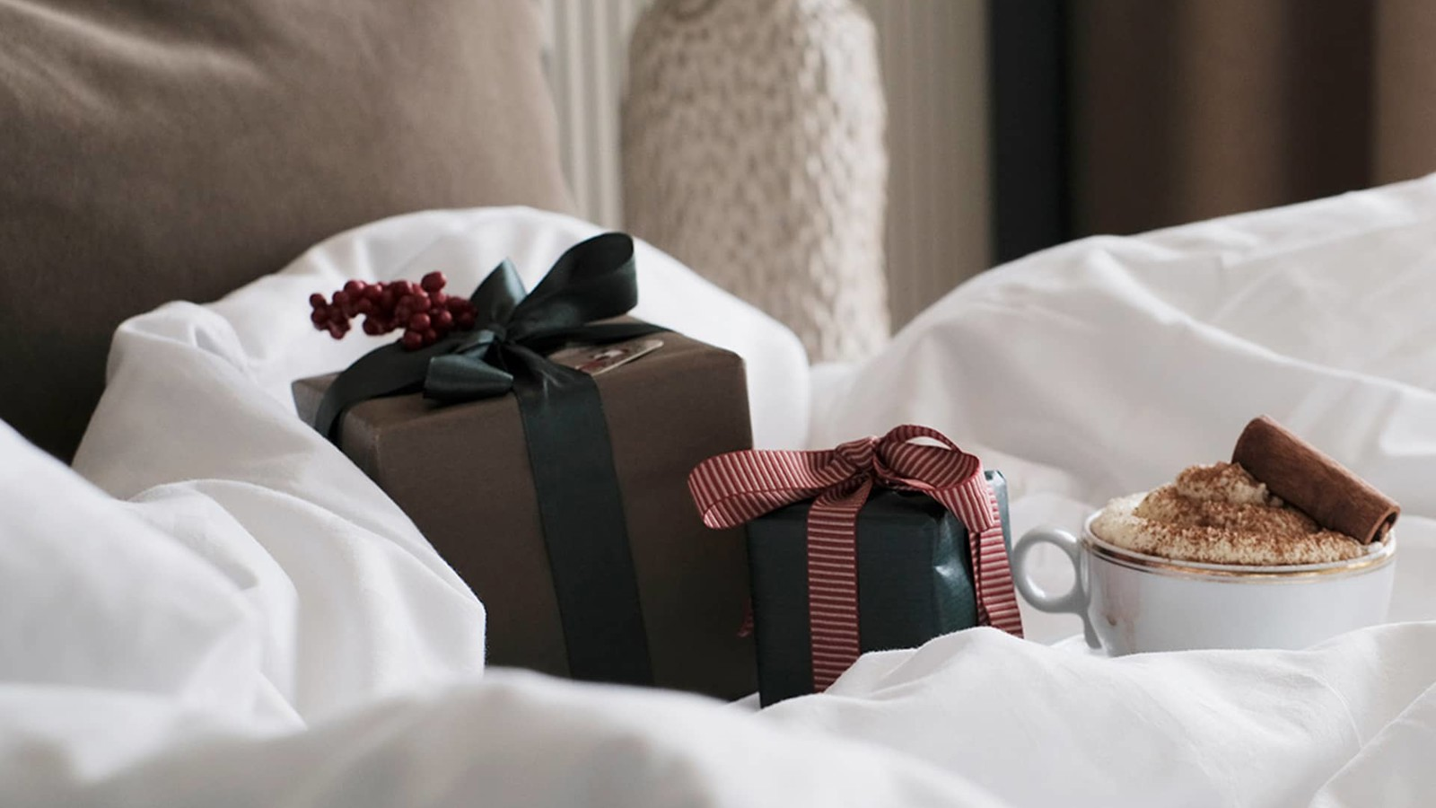 Christmas presents and a cup of hot chocolate on a fluffy hotel bed