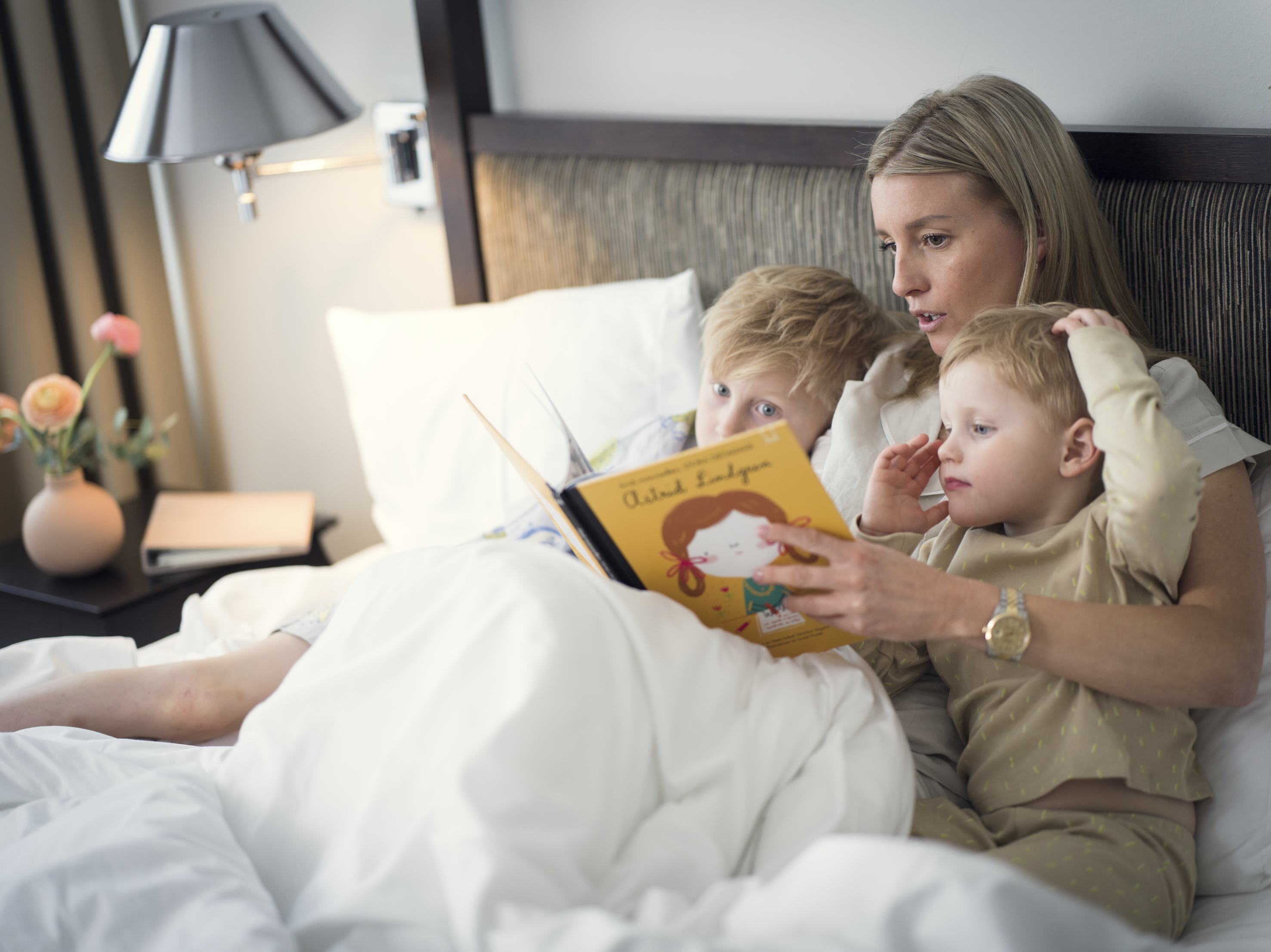Kvinna läser bok för två barn i en säng