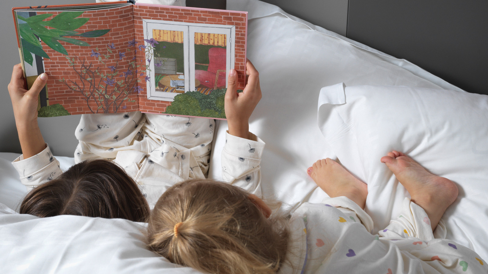 Children reading a book in bed