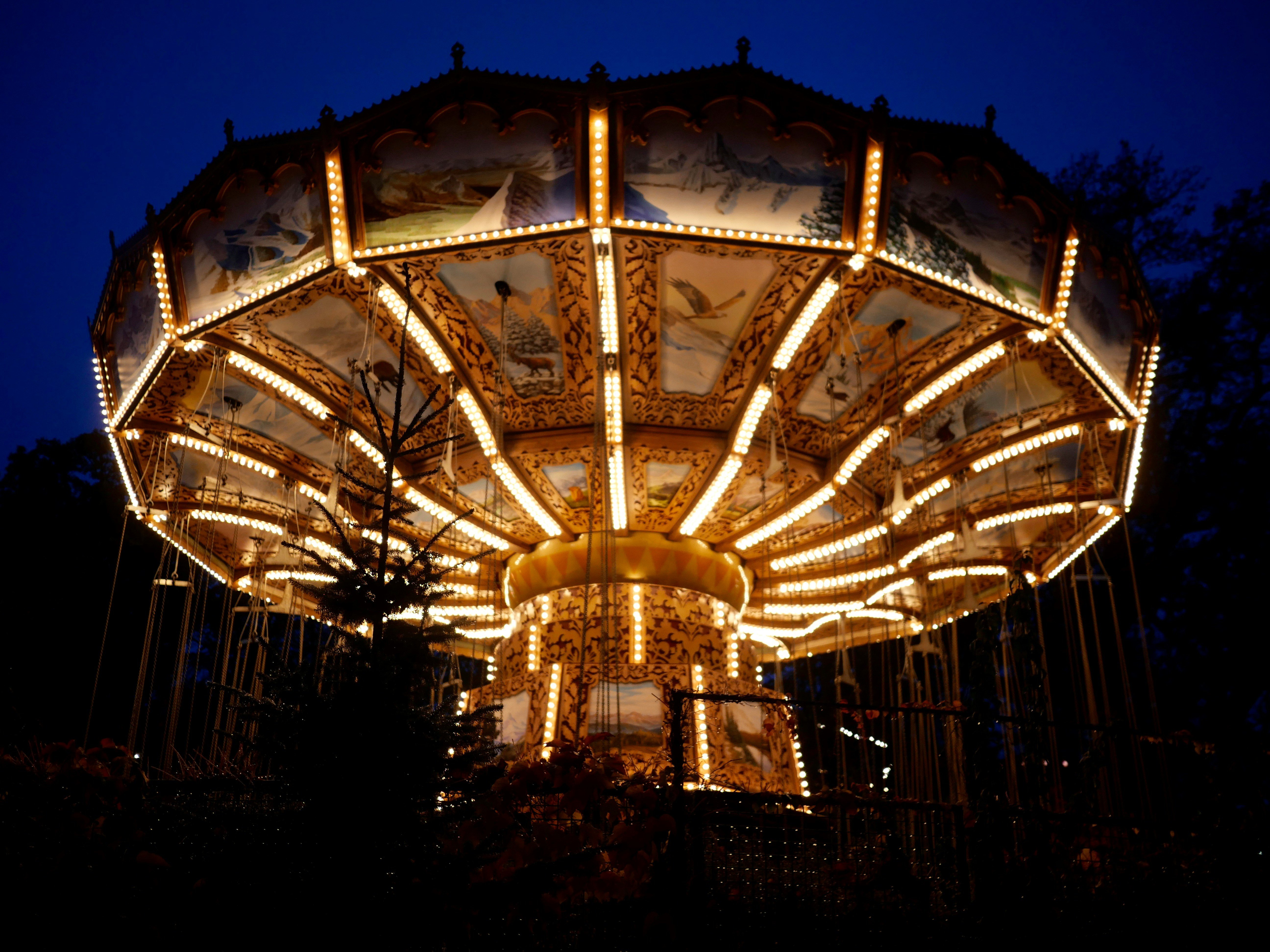 Amusement park carousel with swings spinning in the air on a sunny day, surrounded by trees and blue sky