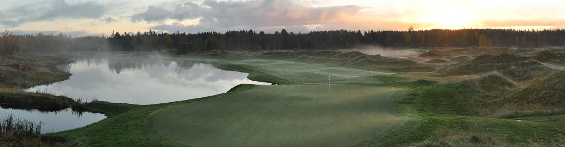 En golfbana omringad med kullar och skog
